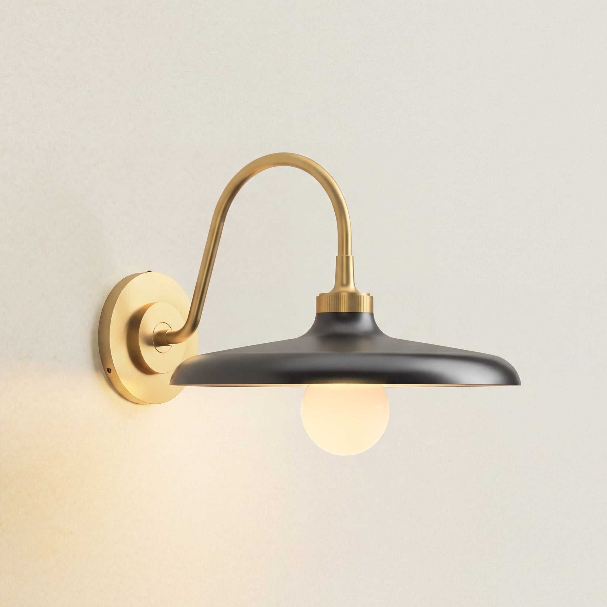 arcoris metal sconce wall-mounted light fixture with black shade and gold arm, on